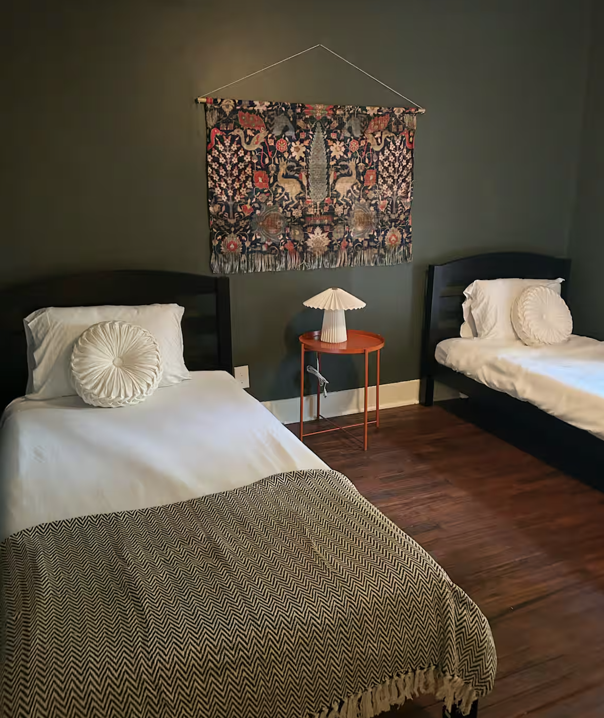 Twin bedroom with vintage tapestry and hardwood floors