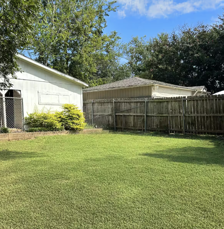 Private fenced backyard with green grass