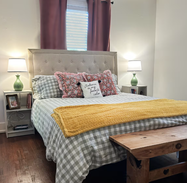Second queen bedroom with tufted headboard, gingham bedding, and mustard throw