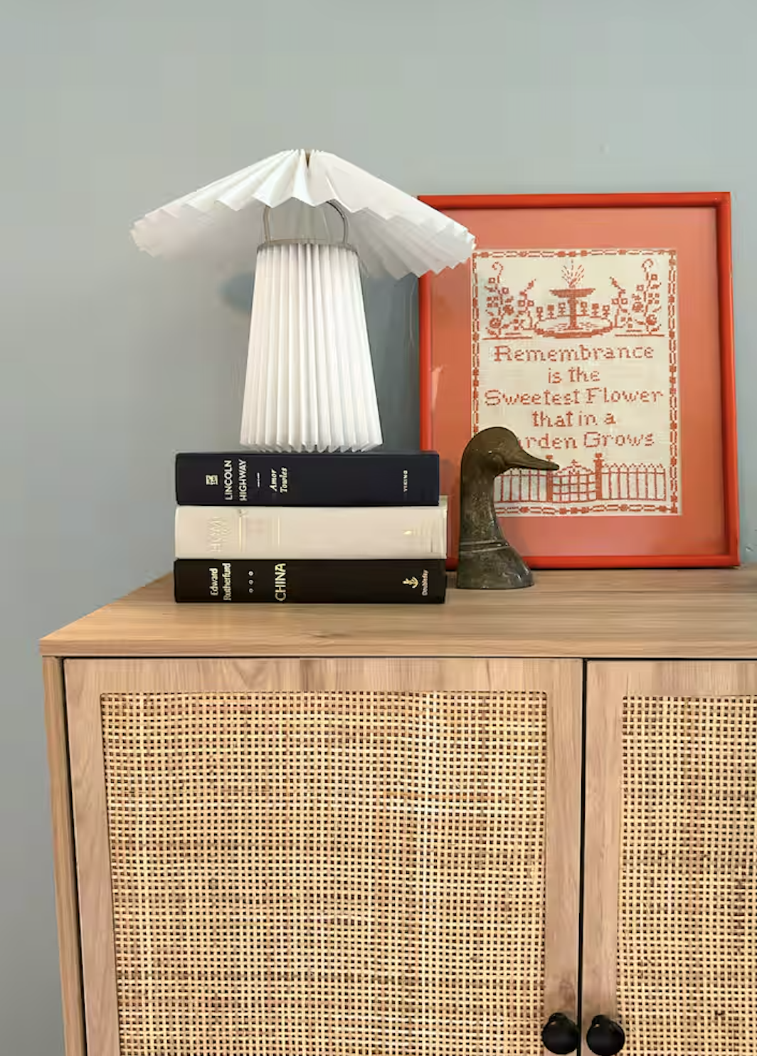 Cane sideboard with pleated lamp and stitched art